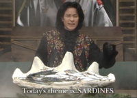 Chairman Kaga of Iron Chef unveils a pile of sardines. Subtitles read, 'Today's theme is...SARDINES.'