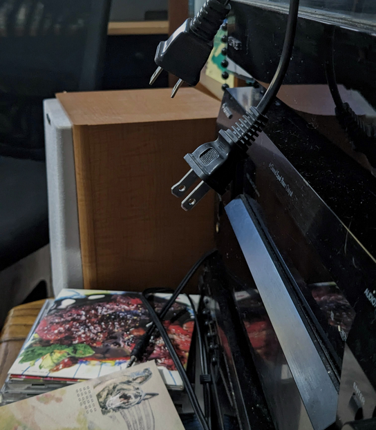 A stack of various audio equipment with power cables dangling in the foreground.